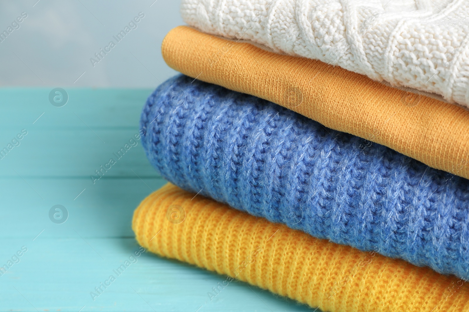 Photo of Stack of folded knitted sweaters on table, closeup