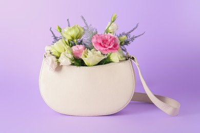 Photo of Stylish women's bag with beautiful flowers on violet background