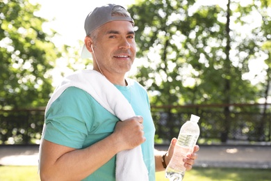 Photo of Handsome mature man with bottle of water in park. Healthy lifestyle