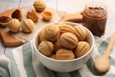 Delicious nut shaped cookies with boiled condensed milk on table, closeup