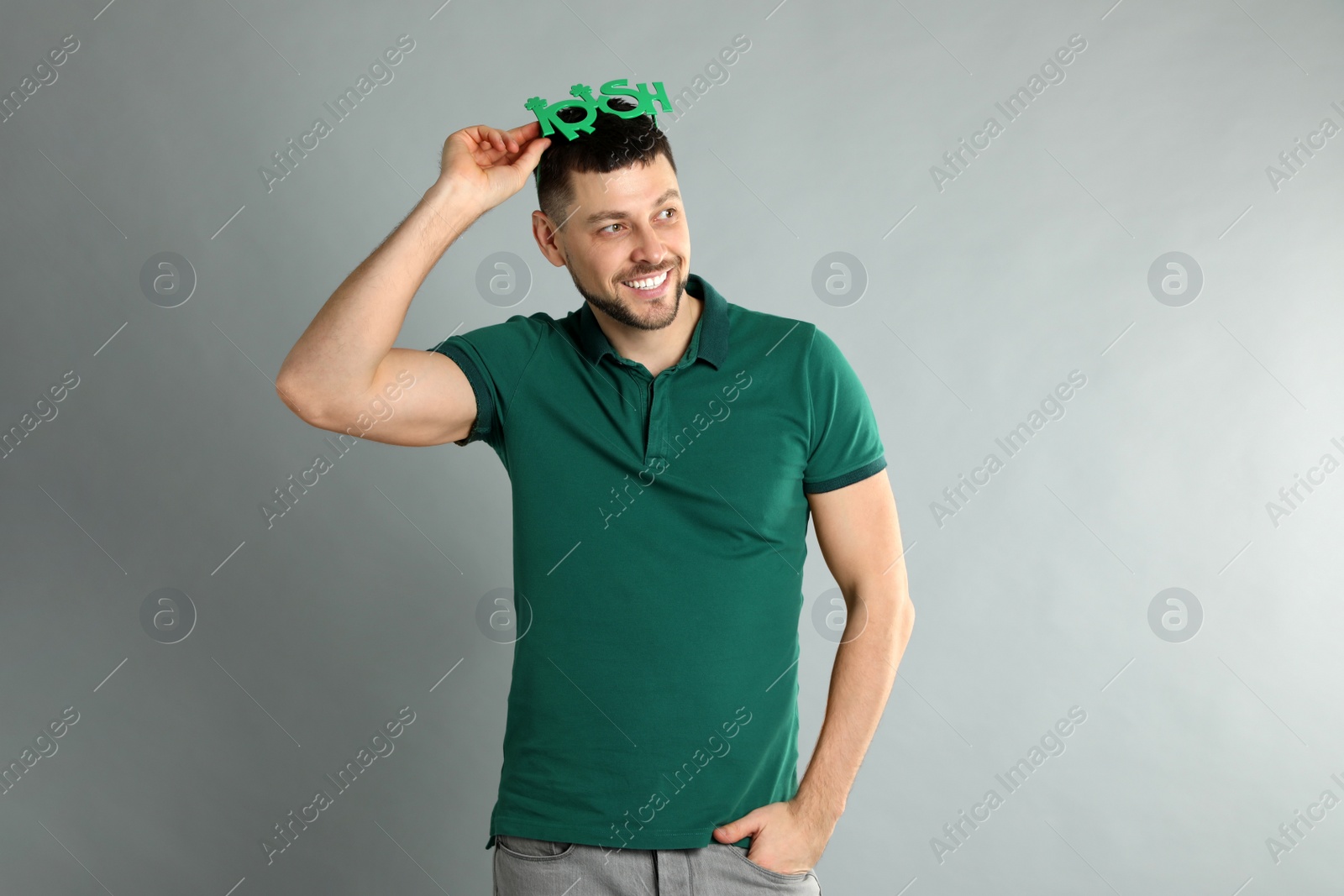 Photo of Happy man in green shirt and party glasses on light grey background. St Patrick's Day celebration