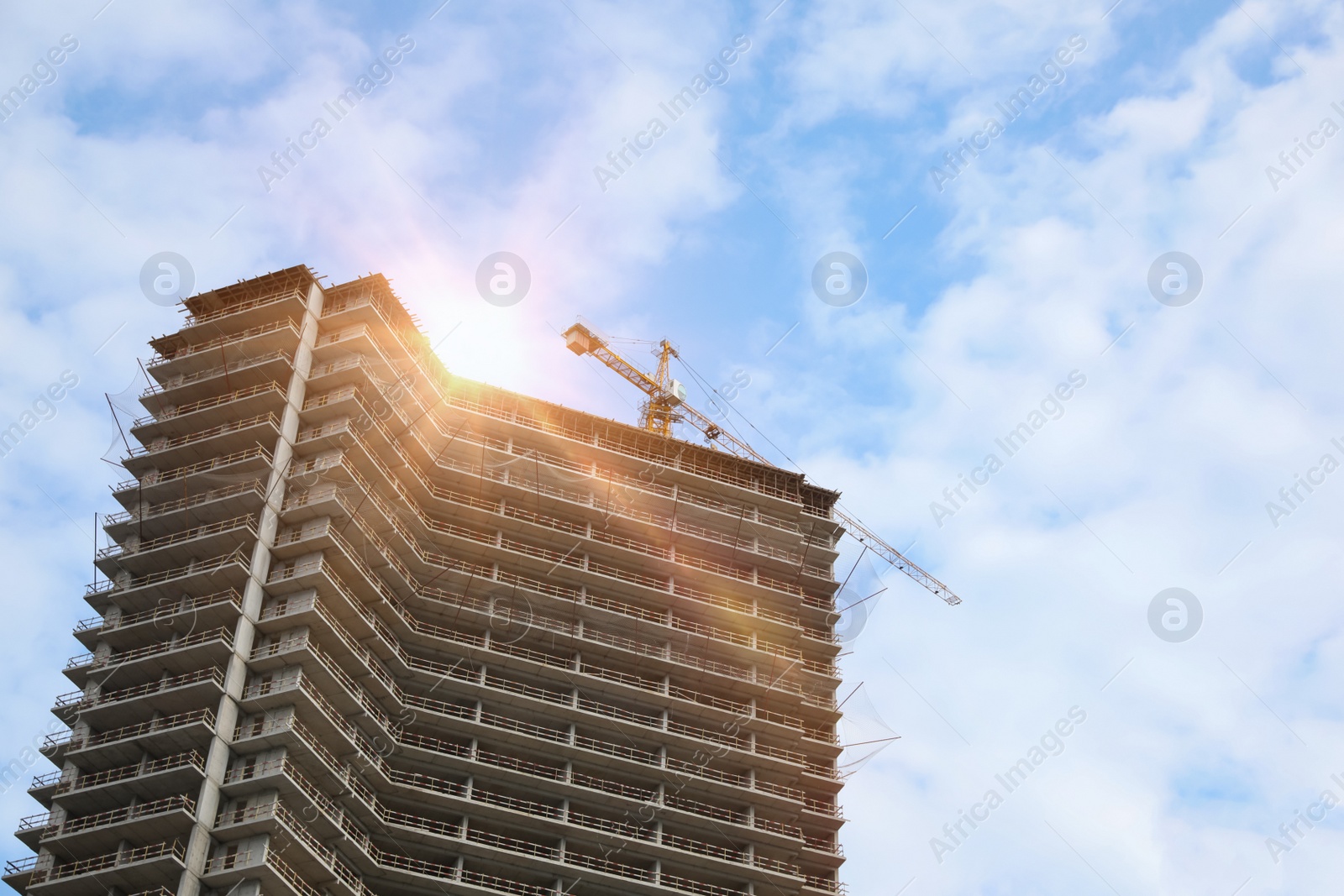 Photo of Multistoried residential building and construction crane outdoors, low angle view