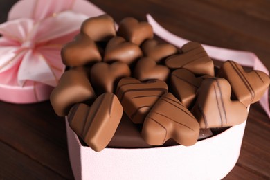 Photo of Beautiful heart shaped chocolate candies in box on wooden table, closeup