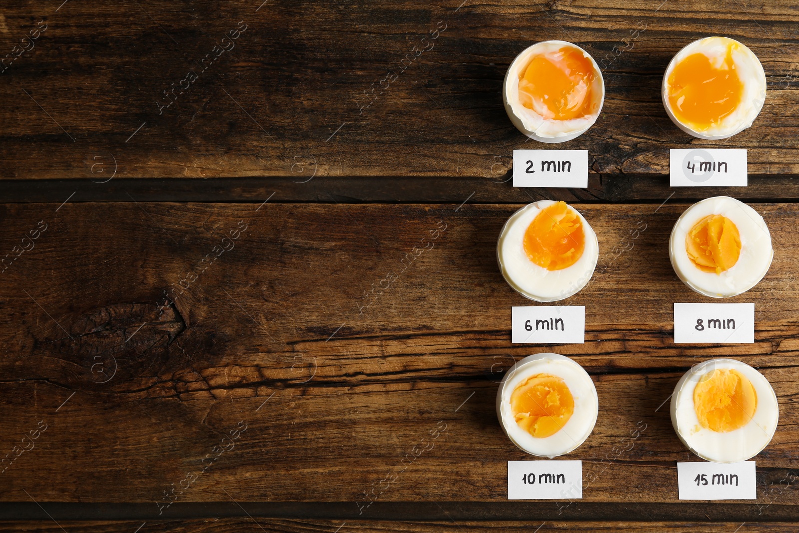 Photo of Different cooking time and readiness stages of boiled chicken eggs on wooden table, flat lay. Space for text