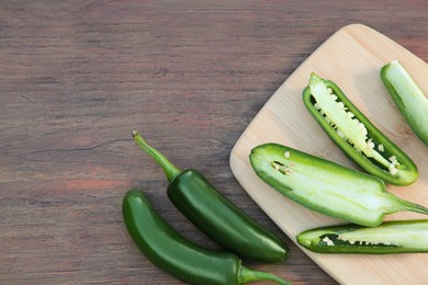 Photo of Fresh green jalapeno peppers on wooden table, flat lay. Space for text