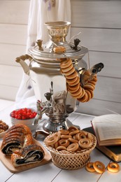 Photo of Traditional Russian samovar and treats on white wooden table