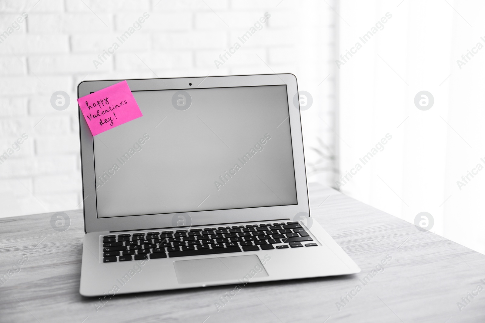 Photo of Memory sticker with phrase Happy Valentine's Day on laptop at workplace