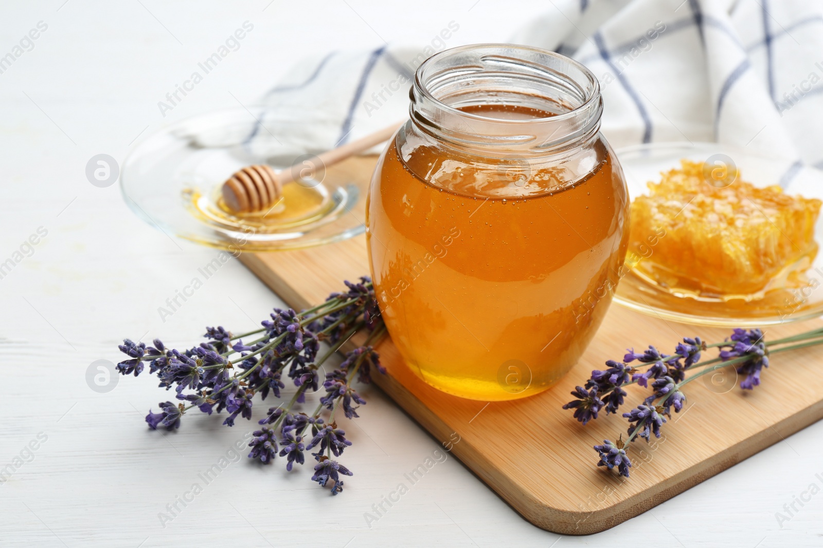 Photo of Tasty honey and lavender flowers on white wooden table