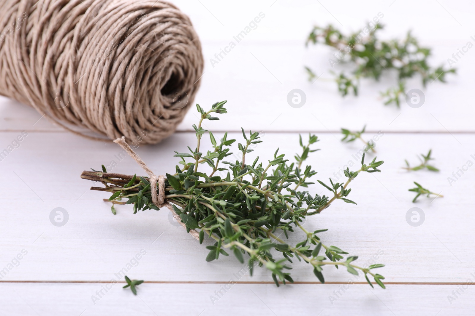 Photo of Bunch of fresh thyme and twine on white wooden table