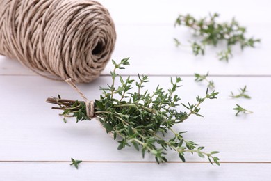 Photo of Bunch of fresh thyme and twine on white wooden table