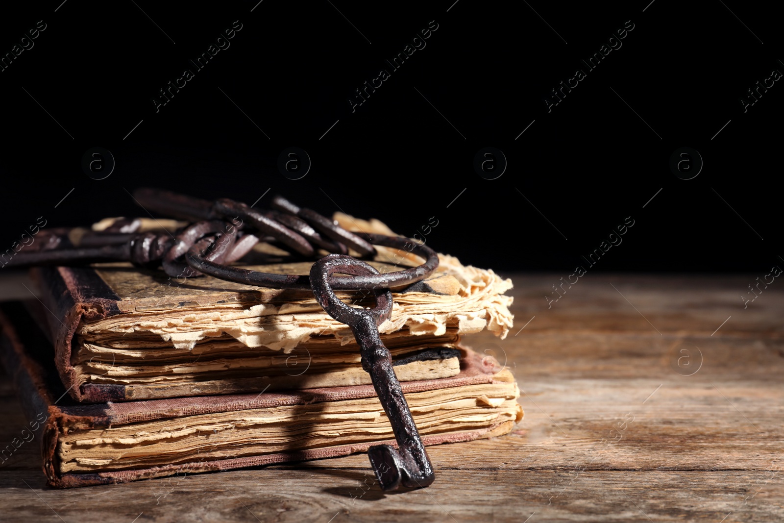 Photo of Bunch of old vintage keys with books on wooden table, space for text