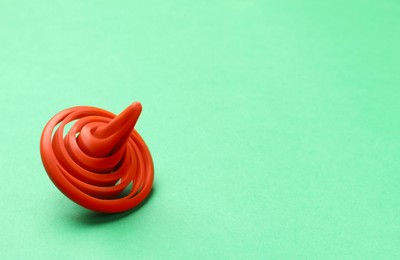 Photo of One orange spinning top on green background, space for text