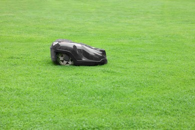 Photo of Modern lawn mower on green grass outdoors. Space for text