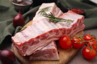 Raw pork ribs, rosemary and tomatoes on table, closeup
