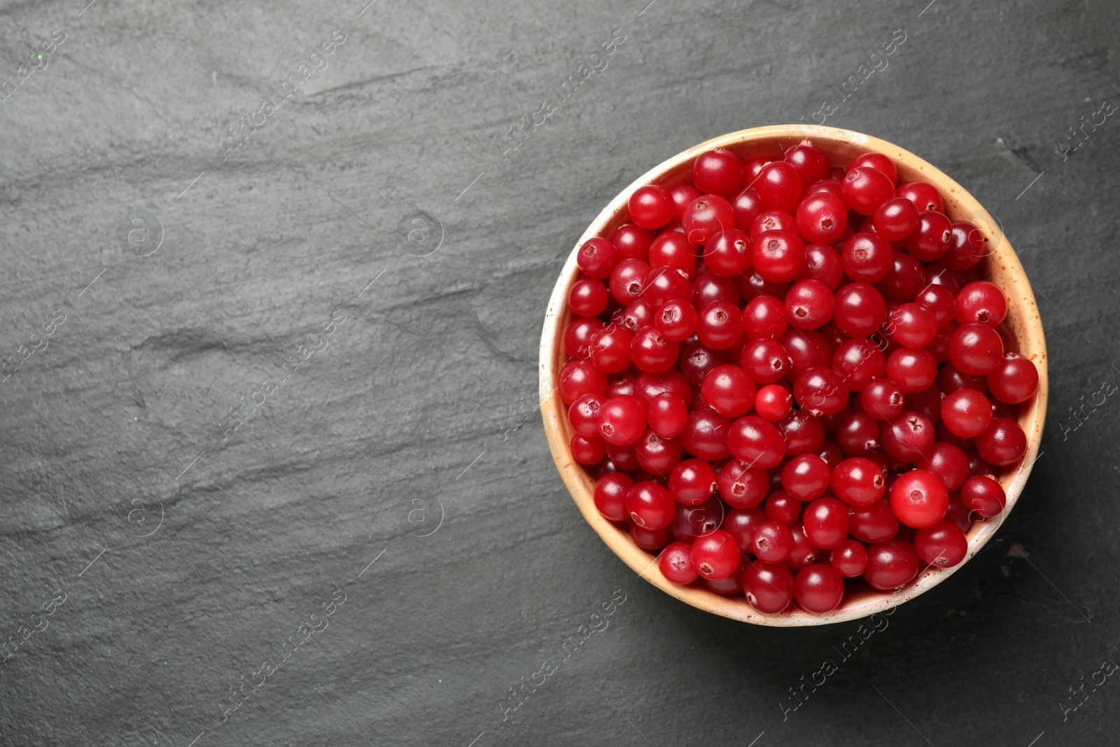 Photo of Tasty ripe cranberries on black table, top view. Space for text