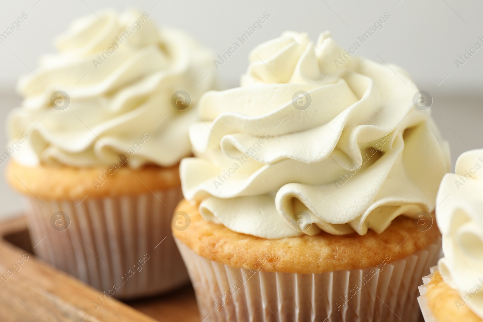 Photo of Tasty cupcakes with vanilla cream on table, closeup