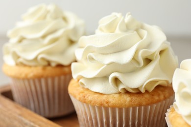 Tasty cupcakes with vanilla cream on table, closeup