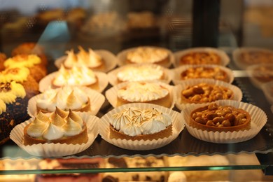 Different tasty tartlets on counter in bakery shop, closeup. Space for text