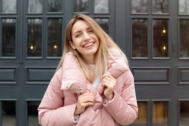 Happy young woman in warm jacket outdoors