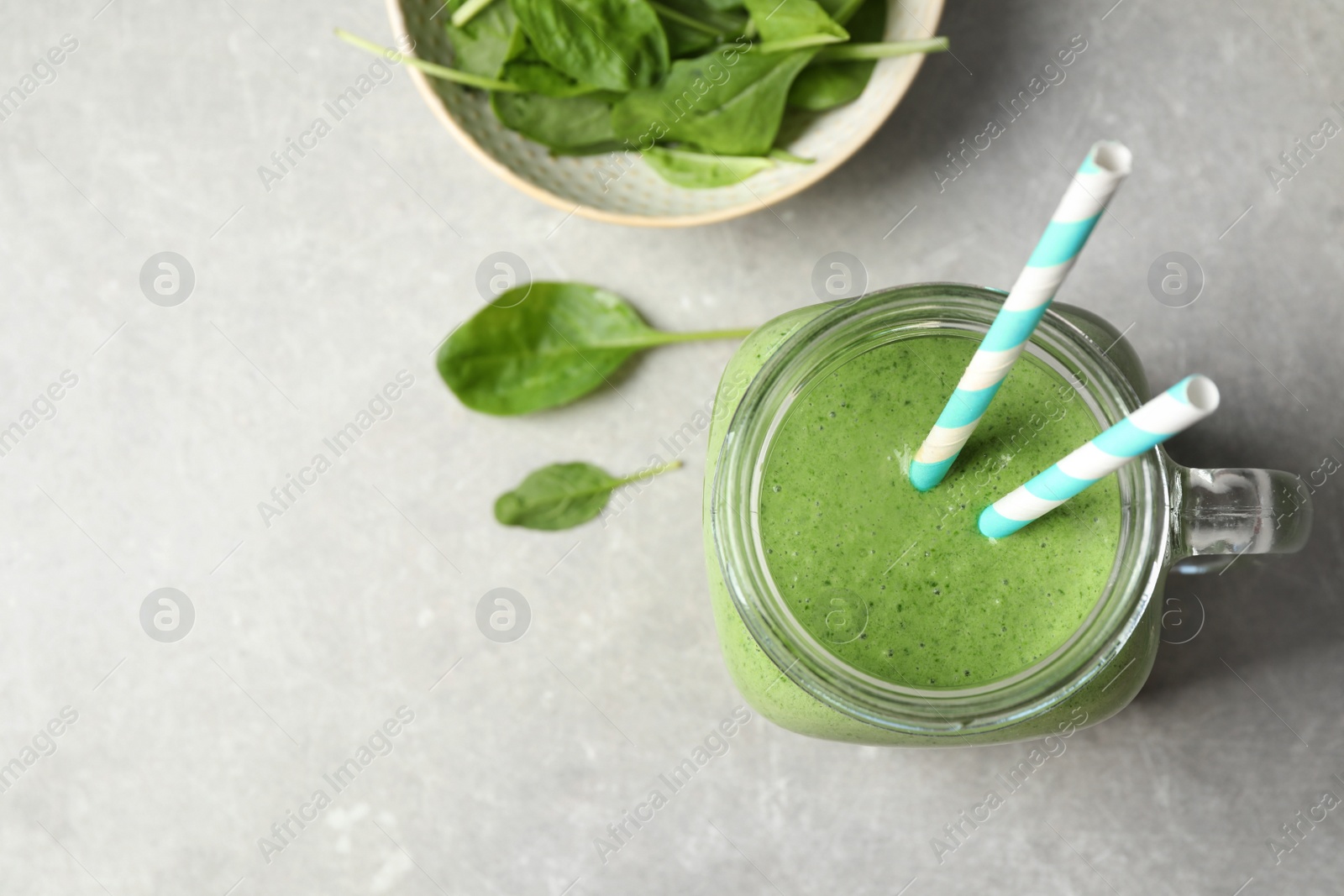 Photo of Flat lay composition with fresh green healthy spinach smoothie on grey table. Space for text