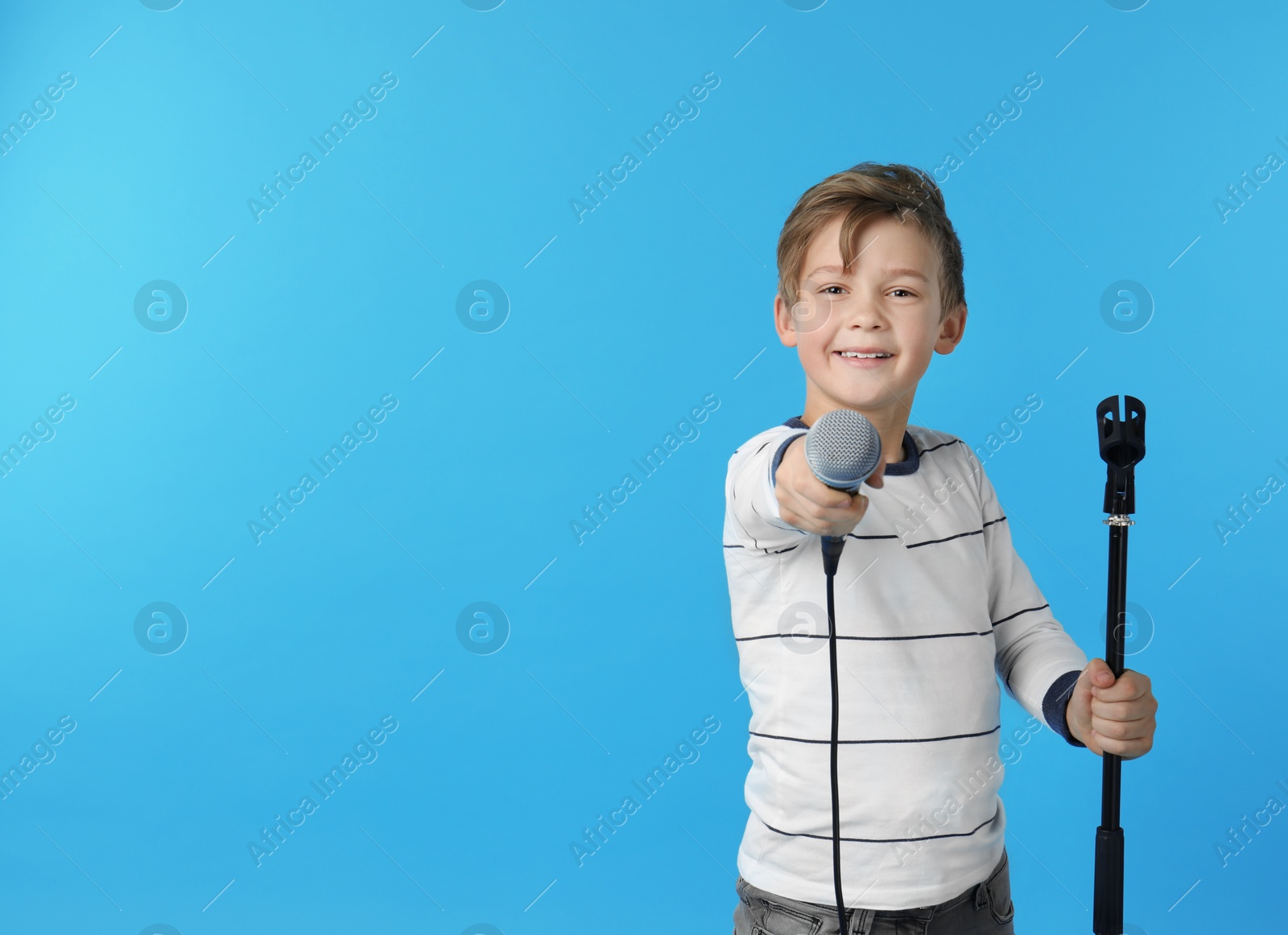 Photo of Cute boy with microphone on color background. Space for text