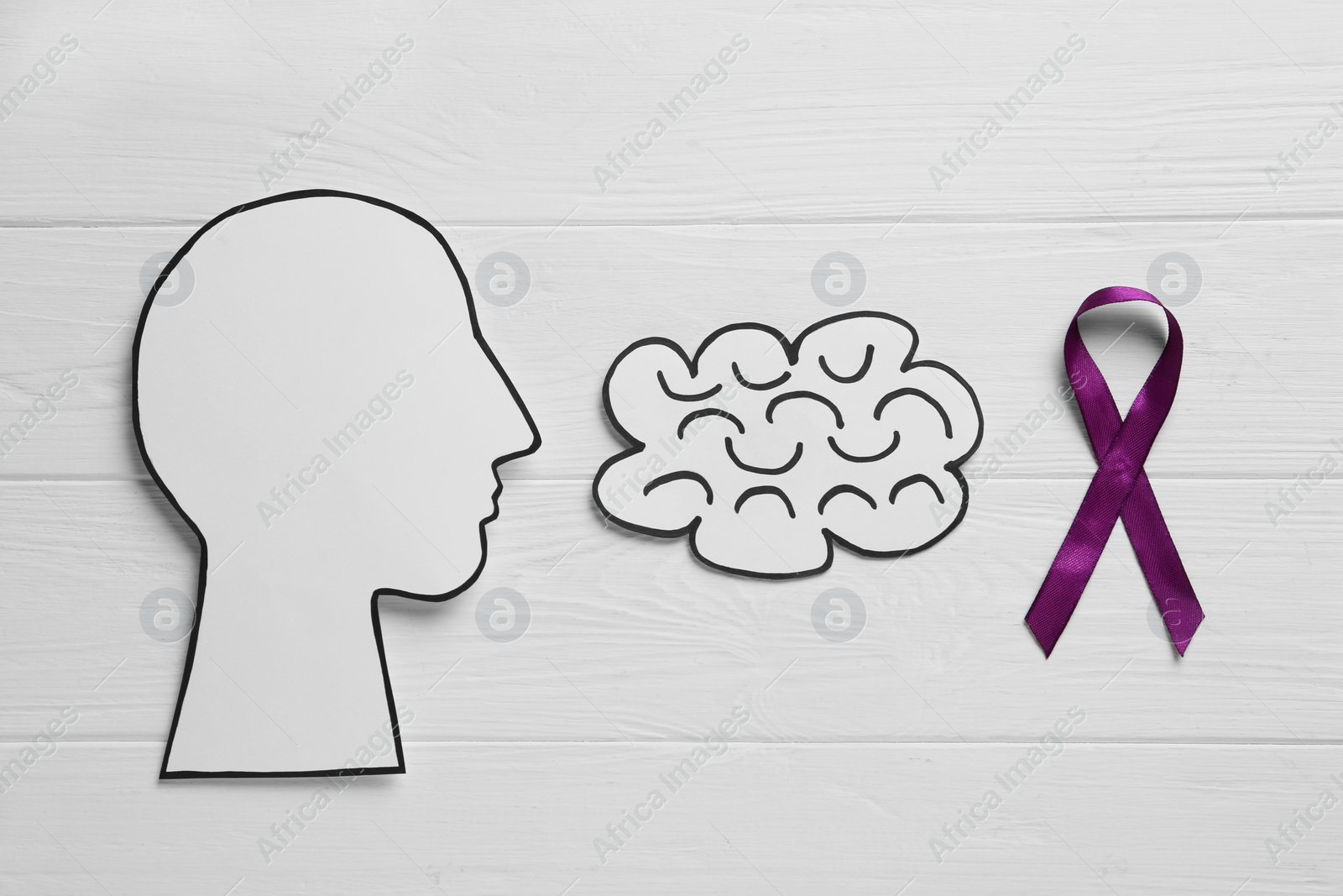 Photo of Human head and brain cutouts near purple ribbon on white wooden background, flat lay. Epilepsy awareness