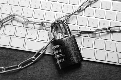Photo of Cyber security. Metal combination padlock with chain and keyboard on grey table, top view