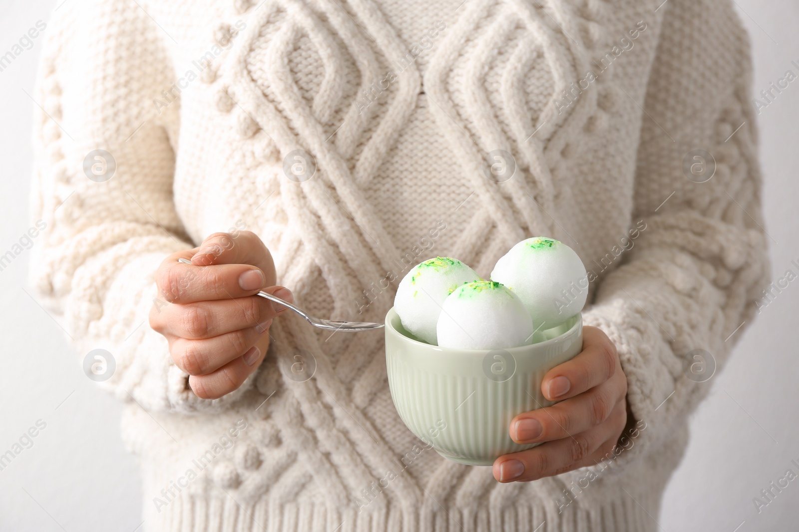 Photo of Woman eating snow ice cream from bowl on light background, closeup