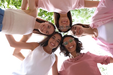 Photo of Happy women joined in circle outdoors, bottom view. Girl power concept