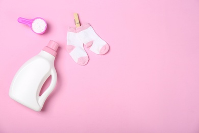 Photo of Flat lay composition with bottle of detergent and children's socks on pink background. Space for text