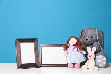 Photo of Photo frames and adorable toys on table against color background, space for text. Child room elements