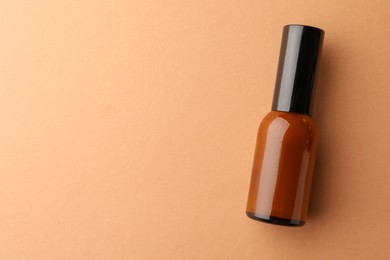 Bottle of face cream on beige background, top view. Space for text