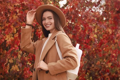 Photo of Beautiful young woman with stylish white backpack in autumn park