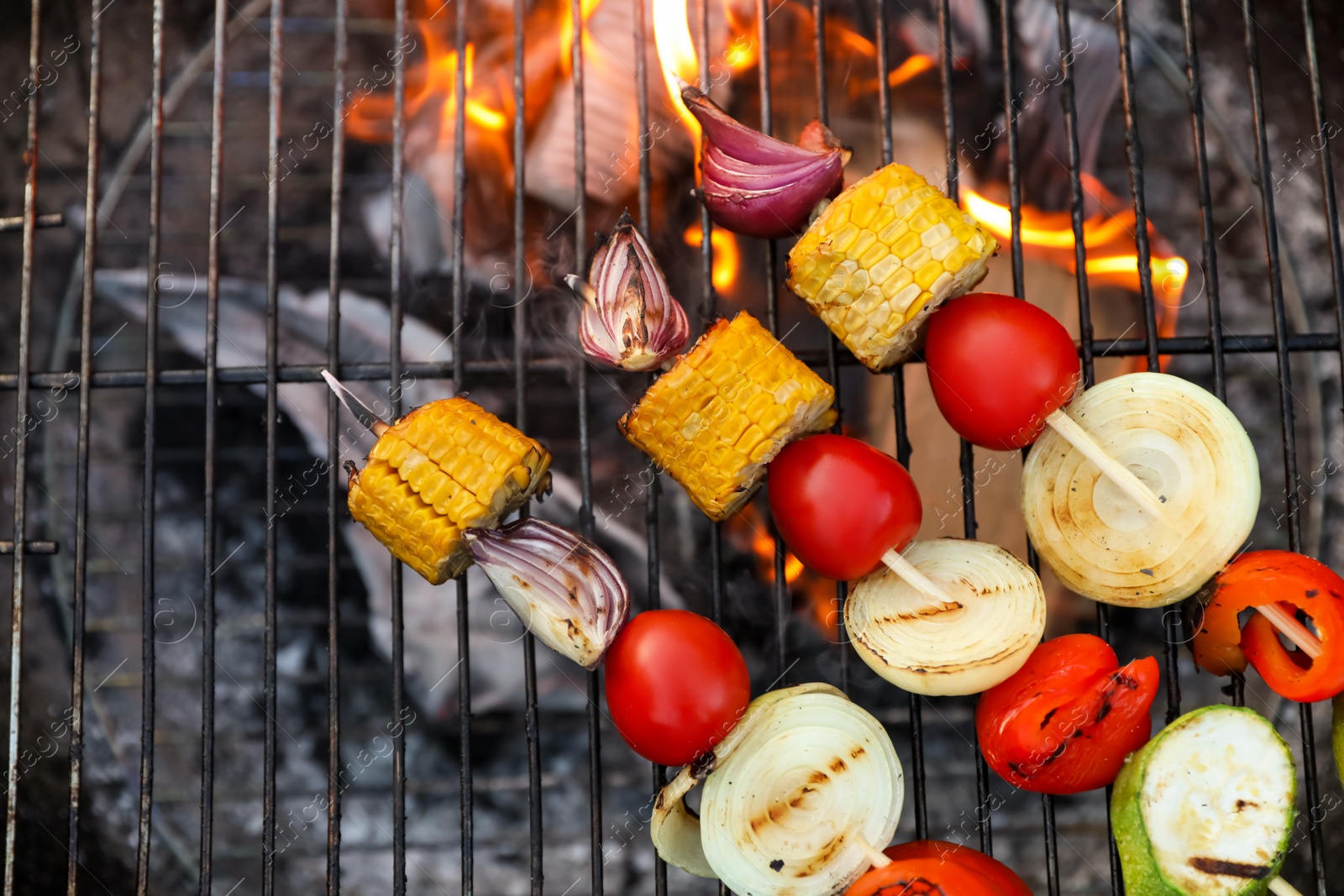 Photo of Skewers with delicious grilled vegetables on barbecue grill, top view