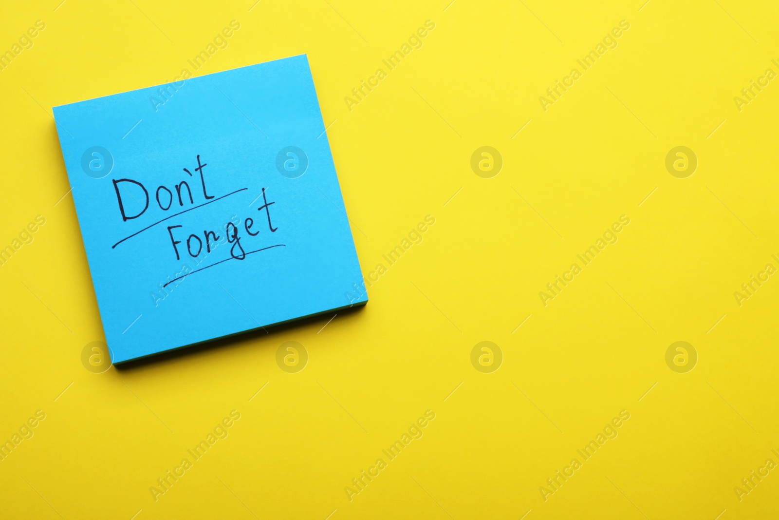 Photo of Paper note with phrase Don' t Forget on yellow background, top view. Space for text