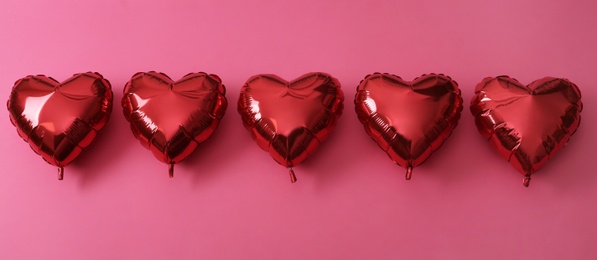 Red heart shaped balloons on pink background, flat lay. Saint Valentine's day celebration