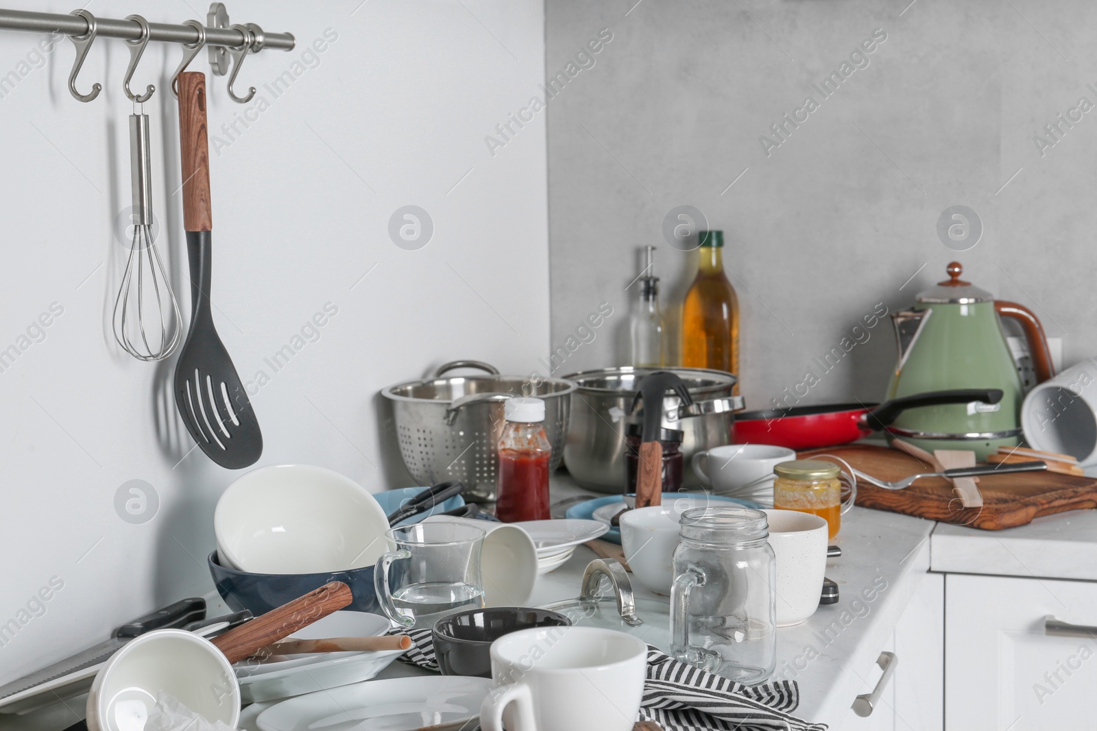 Photo of Many dirty utensils, cookware and dishware on countertop in messy kitchen