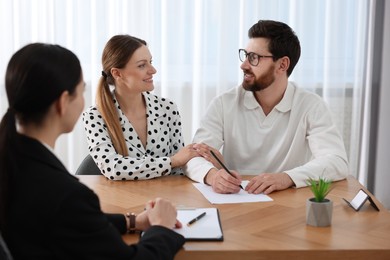 Photo of Couple signing document while having meeting with lawyer in office