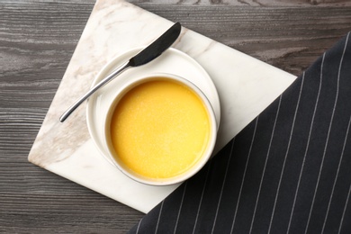 Photo of Flat lay composition with bowl of melting butter on wooden table