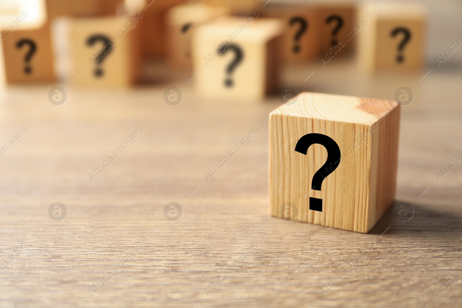 Photo of Cube with question mark on wooden background. Space for text