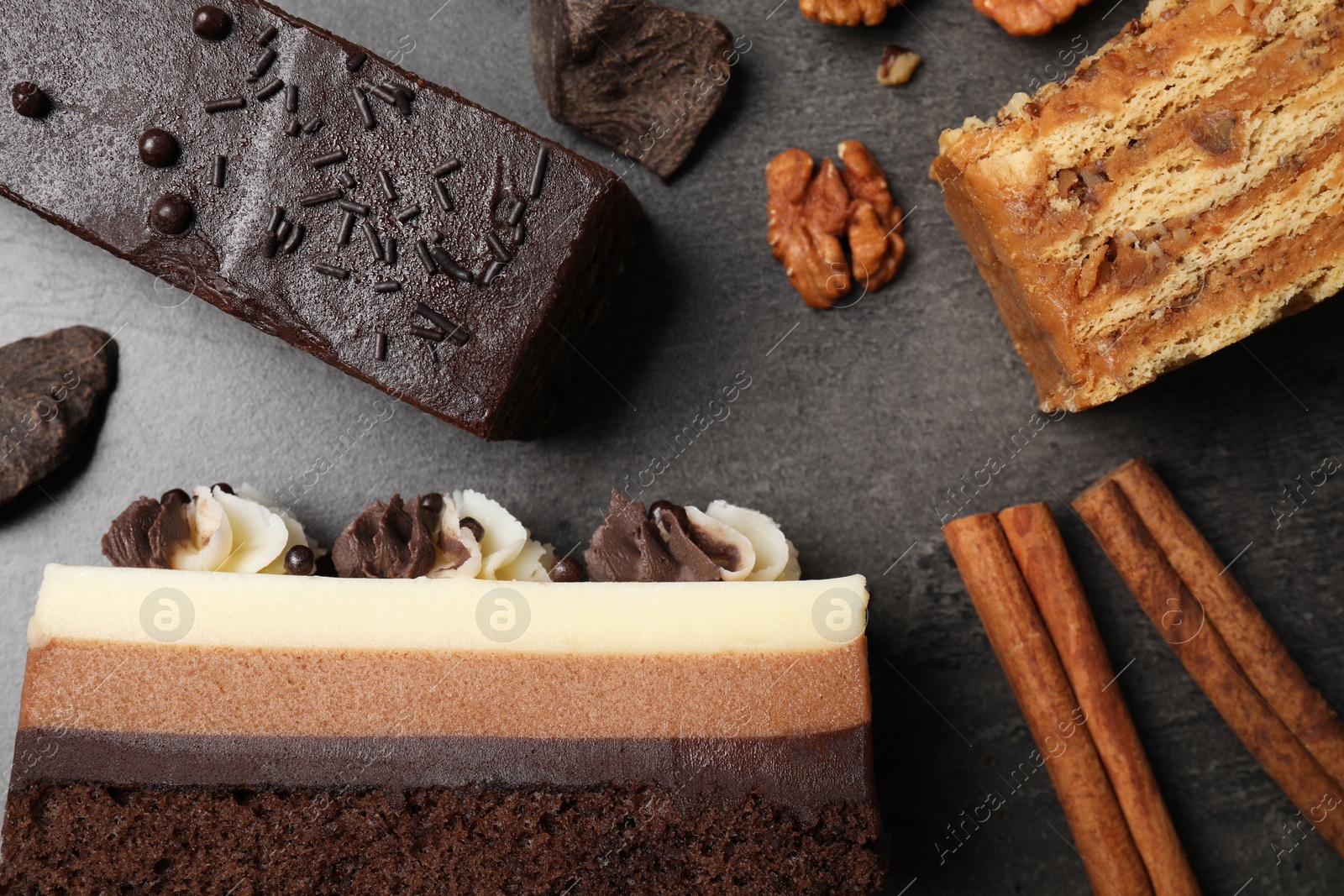 Photo of Different delicious cakes and ingredients on grey table, flat lay