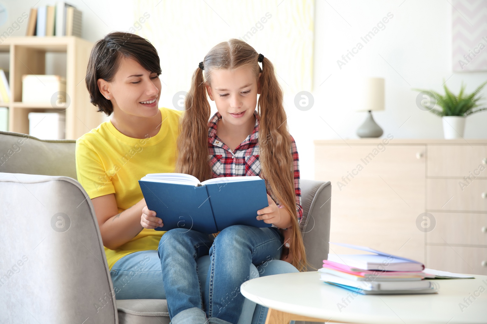 Photo of Young woman helping her child with homework at home. Elementary school