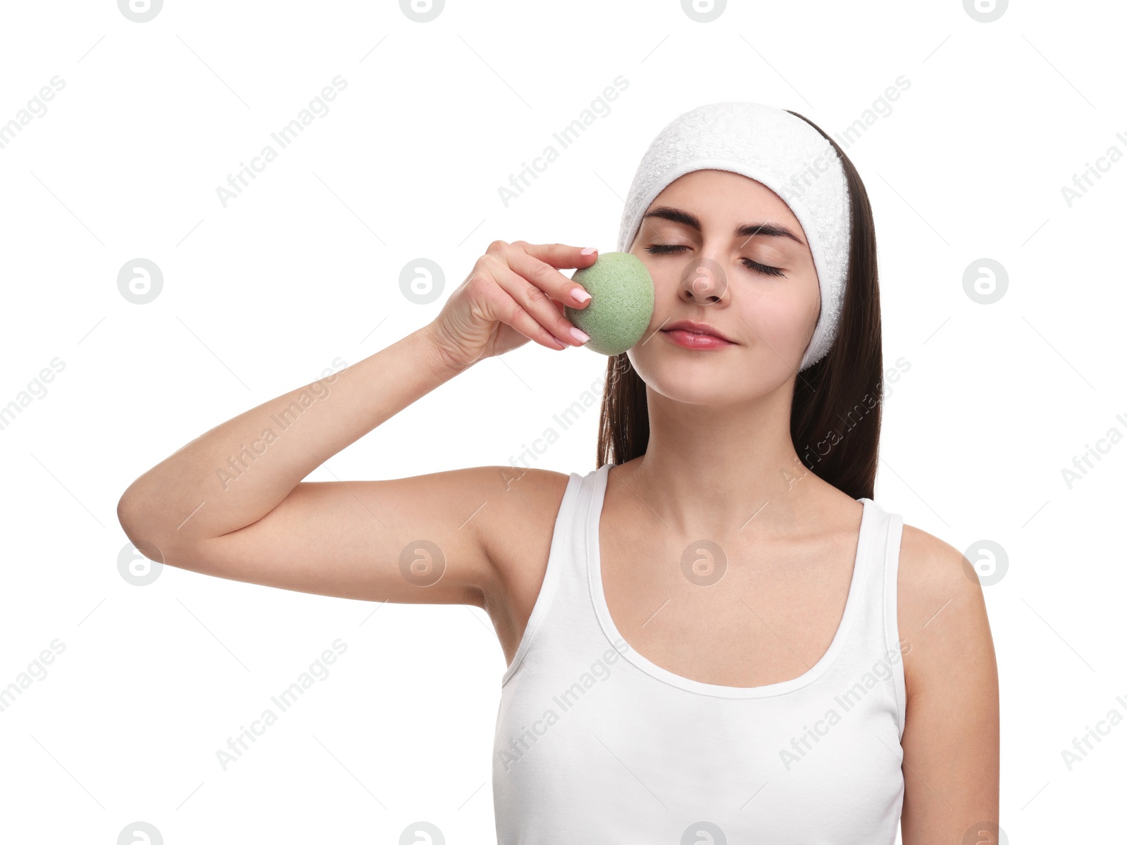 Photo of Young woman with headband washing her face using sponge on white background