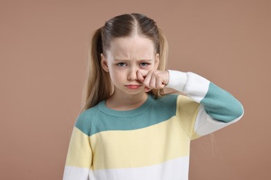 Photo of Portrait of sad girl on light brown background