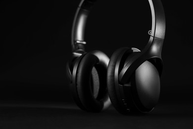 Photo of Modern wireless headphones on black background, closeup