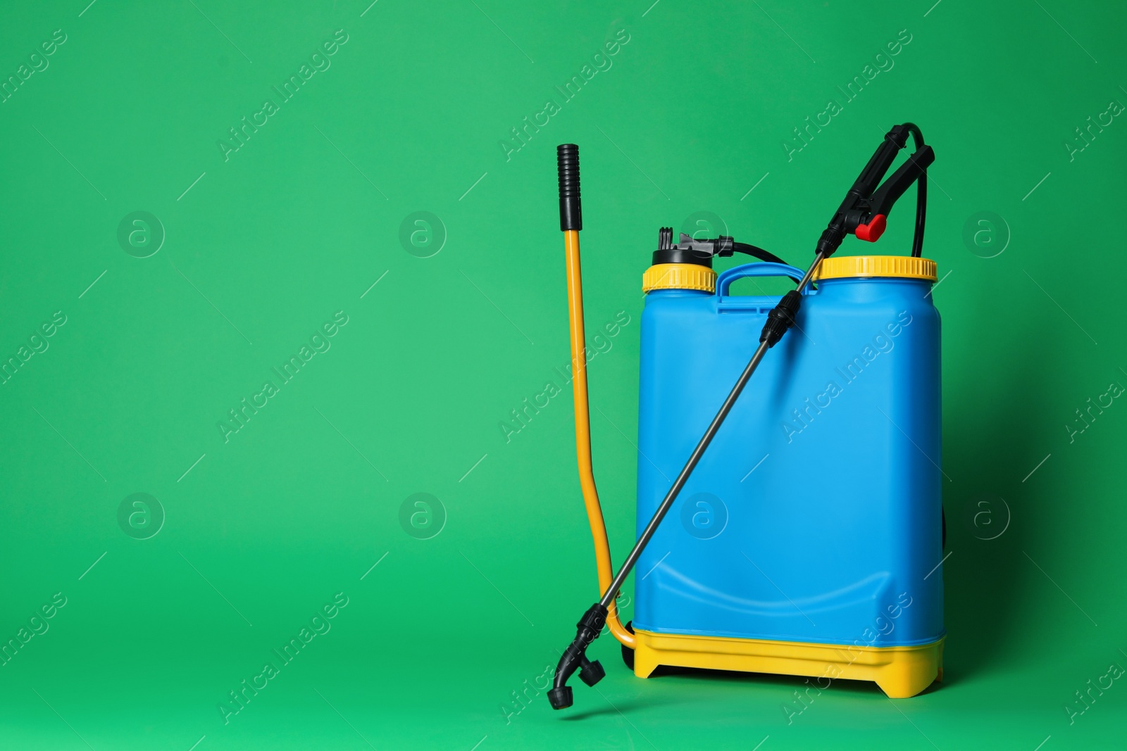 Photo of Manual insecticide sprayer on green background, space for text. Pest control