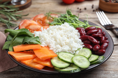 Photo of Tasty rice with beans and vegetables on wooden table, closeup