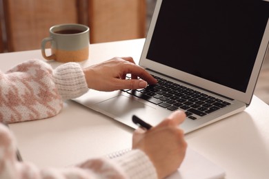 Photo of Woman with modern laptop learning indoors, closeup