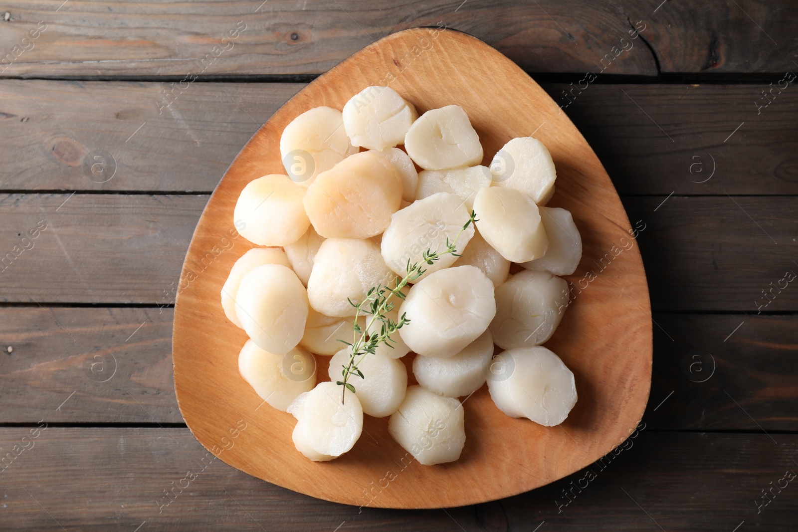 Photo of Fresh raw scallops and thyme on wooden table, top view