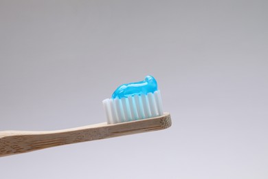 Photo of Wooden brush with toothpaste on grey background, closeup